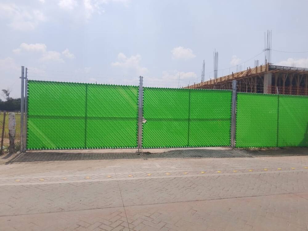 Portón de malla ciclónica con cintillo verde instalado en obra, Querétaro