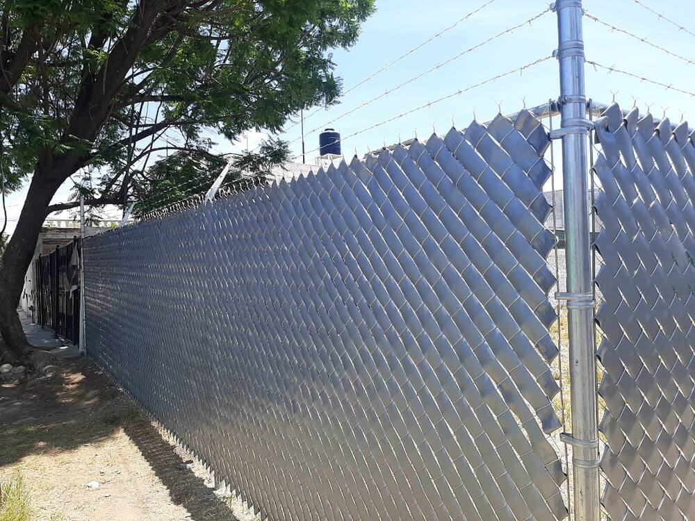 Instalación de malla ciclónica con privacidad en banqueta residencial, Querétaro