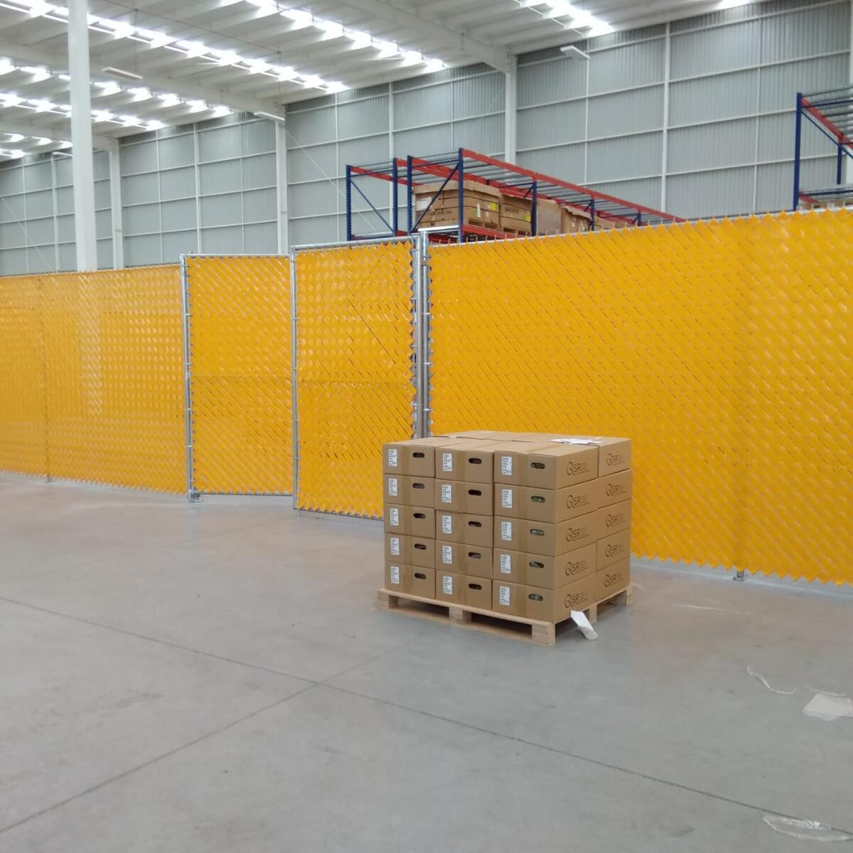 Instalación de malla ciclónica con privacidad amarilla dentro de bodega industrial en Querétaro